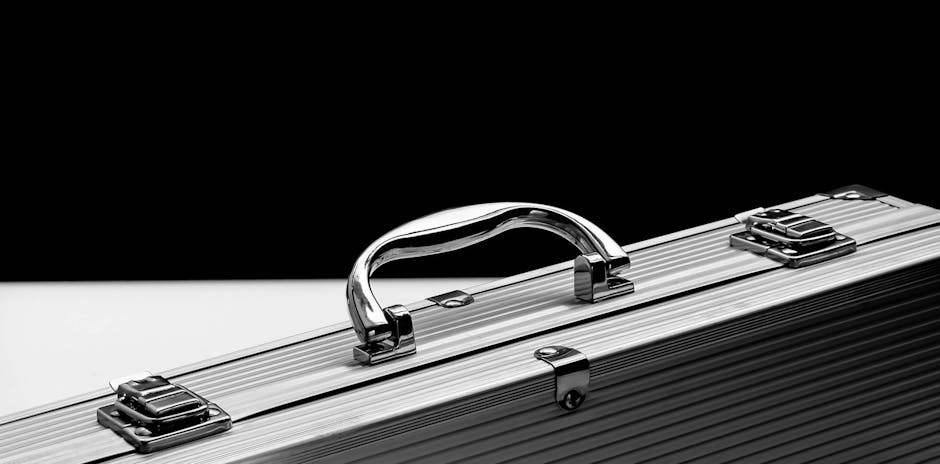 Close-up of a sturdy metal briefcase with a shiny chrome handle on a black and white background.